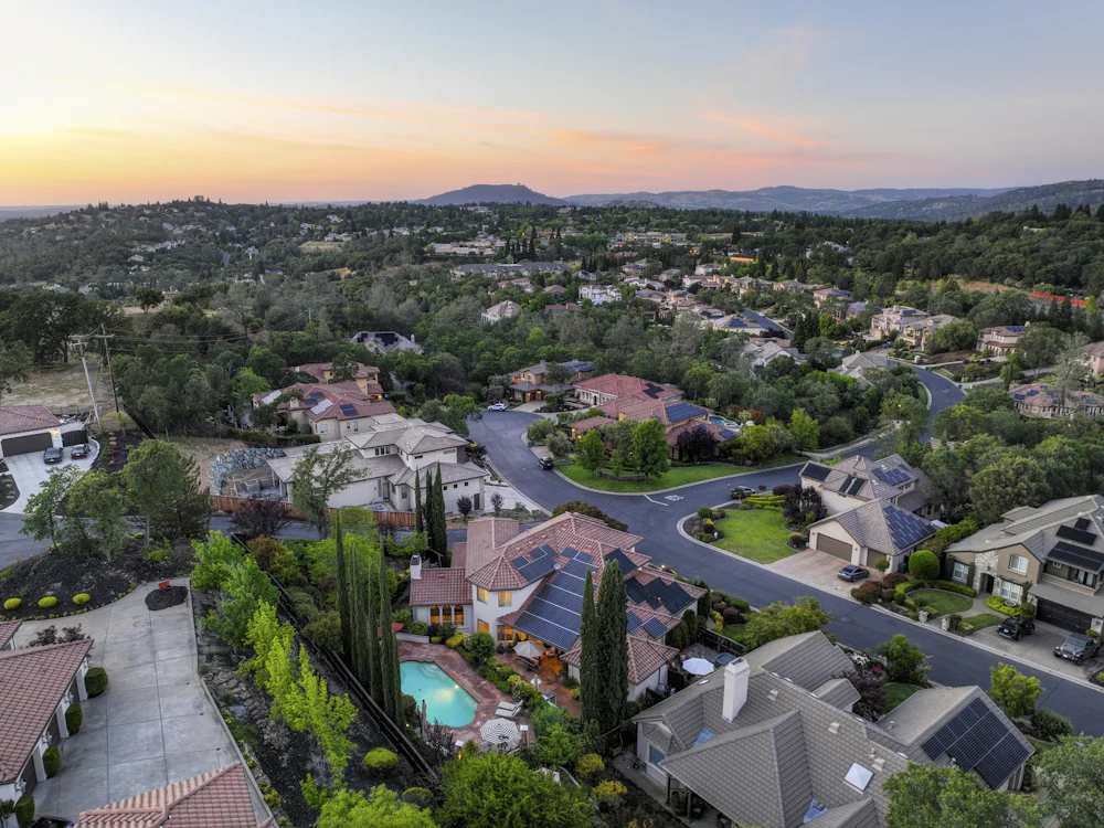 Aerial view of a neighborhood at sunset, with homes along tree-lined streets